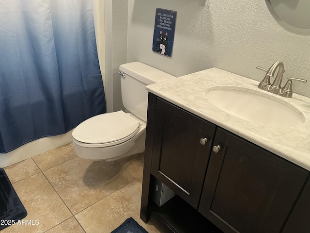 bathroom with a textured wall, vanity, toilet, and tile patterned floors