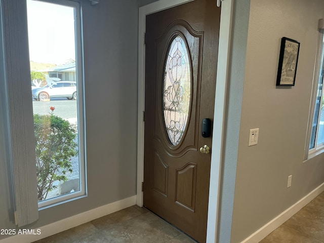 foyer entrance with a healthy amount of sunlight, light tile patterned floors, and baseboards