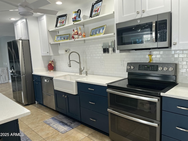 kitchen featuring stainless steel appliances, light countertops, blue cabinetry, white cabinetry, and a sink