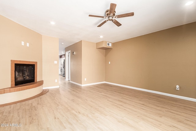 unfurnished living room featuring ceiling fan, light wood-type flooring, and a fireplace