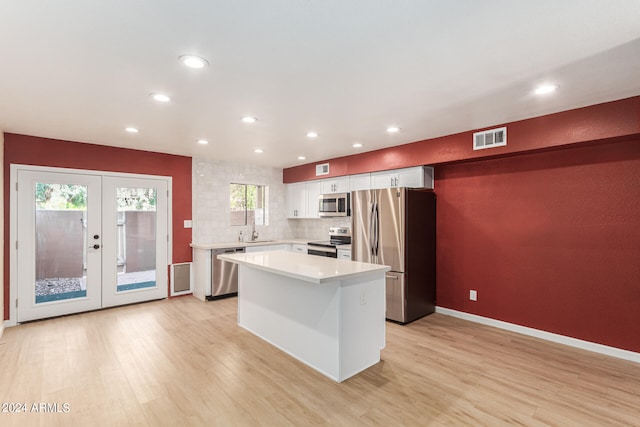 kitchen with french doors, stainless steel appliances, light wood-type flooring, a healthy amount of sunlight, and white cabinetry