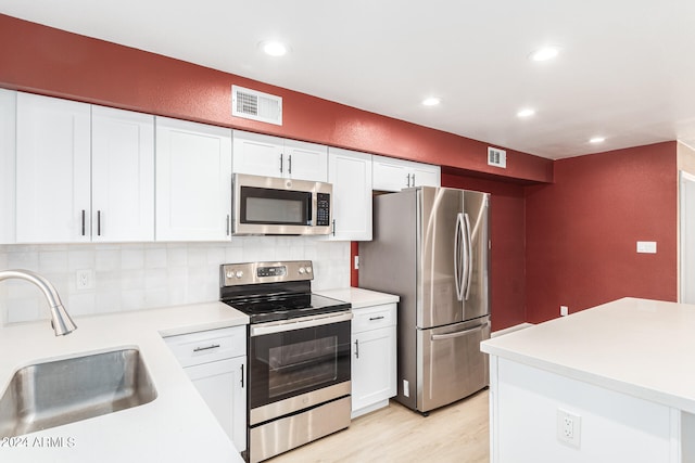 kitchen featuring light hardwood / wood-style flooring, appliances with stainless steel finishes, white cabinets, sink, and tasteful backsplash