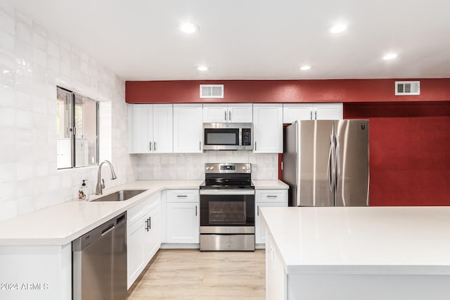 kitchen featuring white cabinets, light hardwood / wood-style flooring, stainless steel appliances, tasteful backsplash, and sink