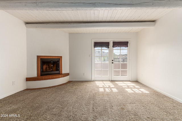 unfurnished living room with beamed ceiling, french doors, carpet floors, and a fireplace