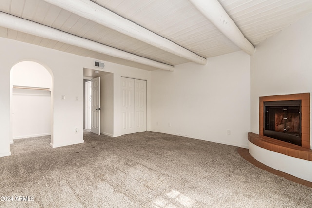 unfurnished living room with beamed ceiling and carpet flooring