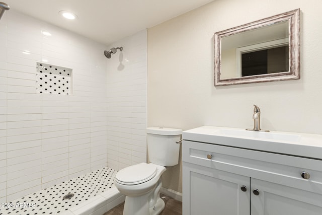 bathroom featuring tiled shower, vanity, and toilet