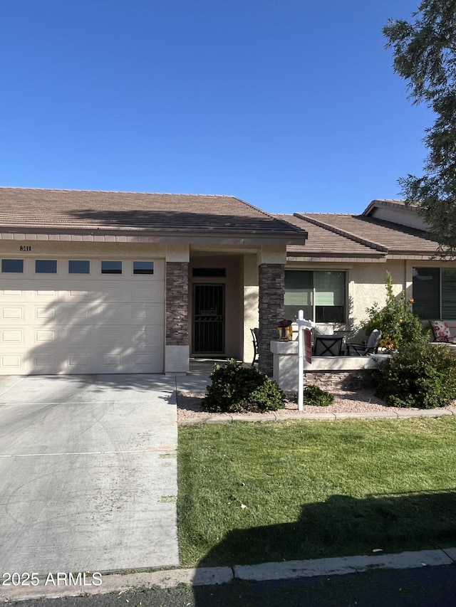 view of front of house with a garage, concrete driveway, stone siding, a front lawn, and stucco siding