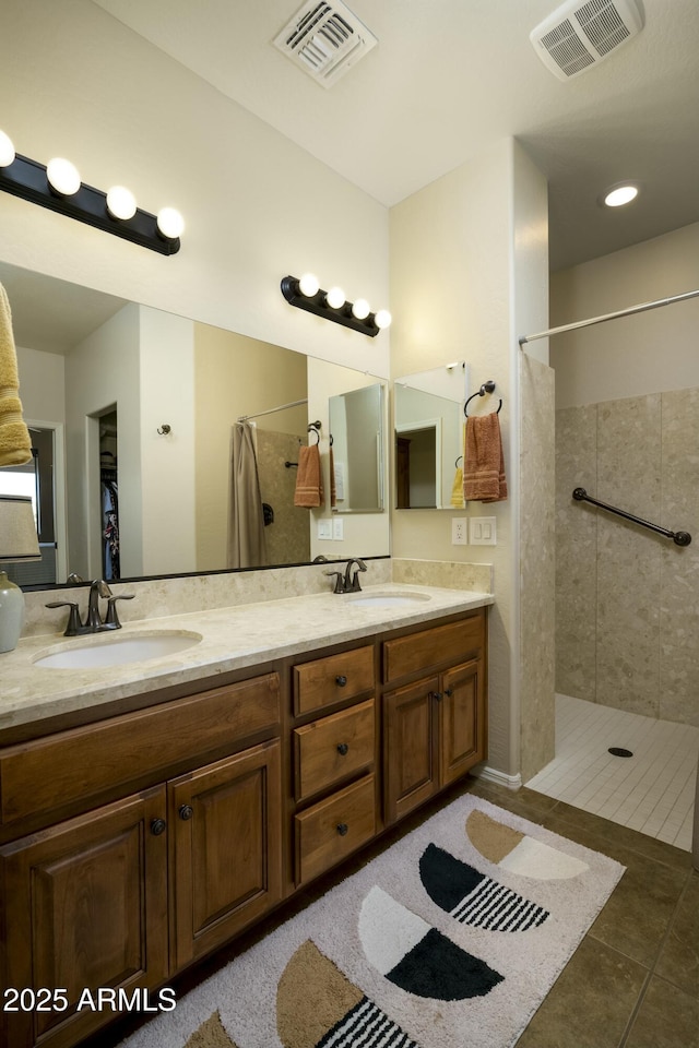 full bathroom featuring visible vents, a tile shower, and a sink