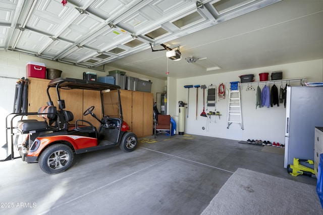 garage featuring freestanding refrigerator, electric water heater, and a garage door opener