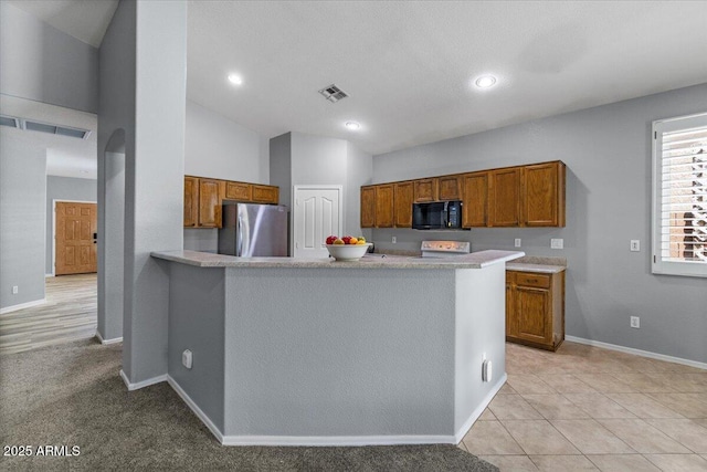 10235 E Jerome Ave, Mesa, AZ 85209 - kitchen with black microwave, freestanding refrigerator, brown cabinetry, light countertops, and a peninsula