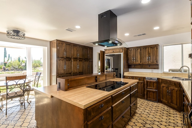 kitchen with a wealth of natural light, island range hood, sink, and black electric cooktop