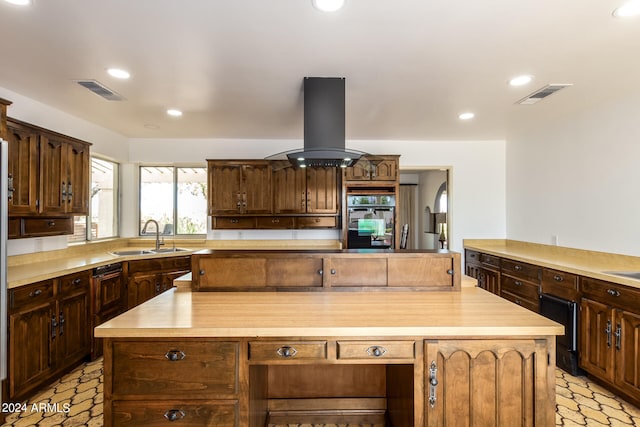 kitchen with island exhaust hood, wood counters, sink, and a kitchen island