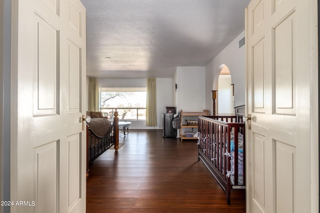 hall featuring dark wood-type flooring and a textured ceiling