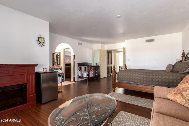 bedroom with dark hardwood / wood-style floors and stainless steel refrigerator