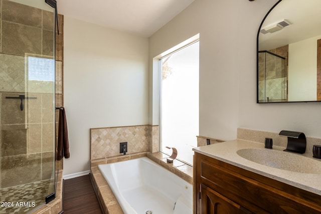 bathroom with vanity, hardwood / wood-style flooring, and plus walk in shower