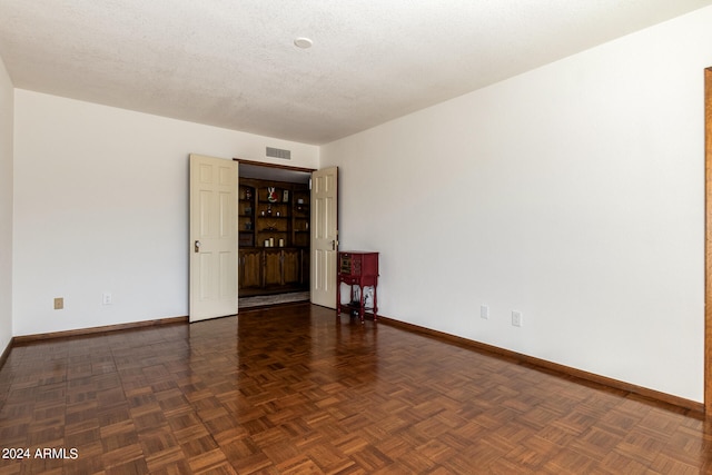 spare room with dark parquet floors and a textured ceiling