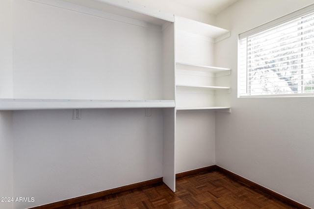 walk in closet with dark parquet flooring