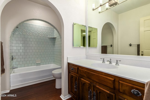 full bathroom with vanity, toilet, tiled shower / bath, and hardwood / wood-style floors