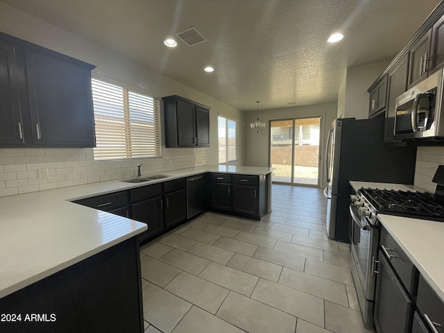 kitchen featuring decorative backsplash, appliances with stainless steel finishes, kitchen peninsula, sink, and decorative light fixtures