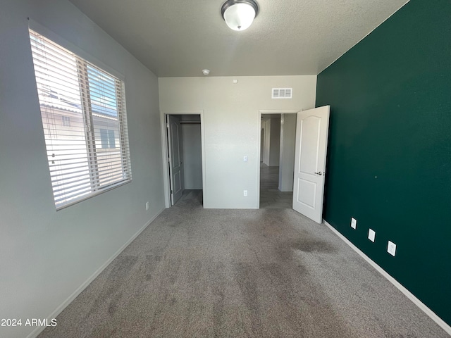 unfurnished bedroom featuring carpet flooring, a textured ceiling, and a closet