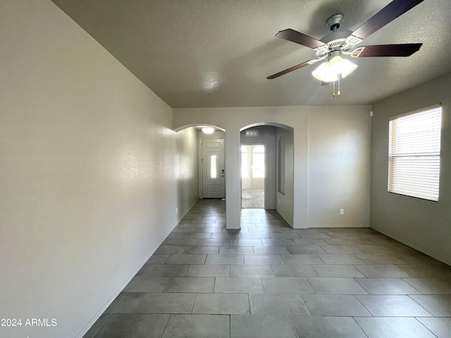 spare room with ceiling fan, a textured ceiling, and a wealth of natural light