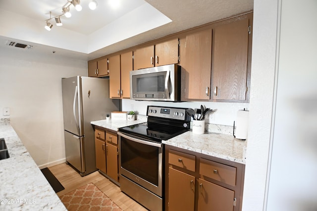 7777 E Main St Unit 227, Scottsdale, AZ 85251 - kitchen with stainless steel appliances, light wood-type flooring, light stone counters, and a tray ceiling