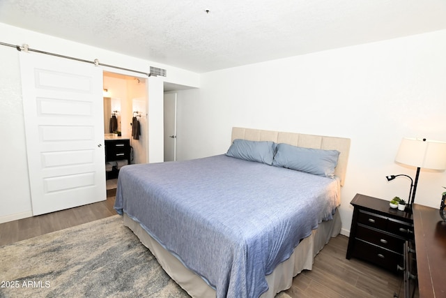 7777 E Main St Unit 227, Scottsdale, AZ 85251 - bedroom with wood finished floors, a barn door, and a textured ceiling