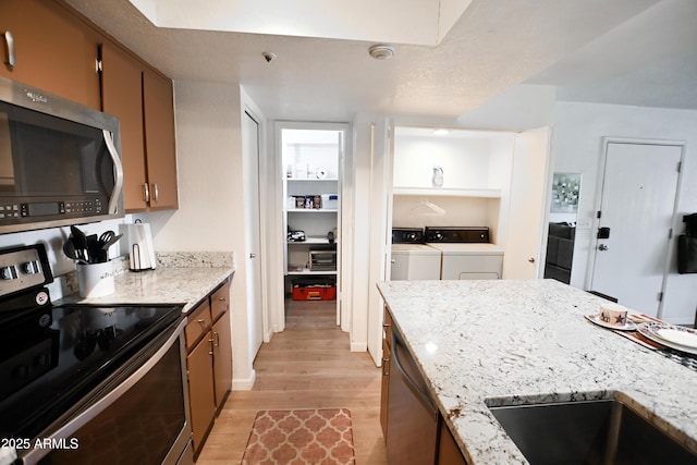7777 E Main St Unit 227, Scottsdale, AZ 85251 - kitchen with stainless steel appliances, independent washer and dryer, light wood-type flooring, and light stone countertops