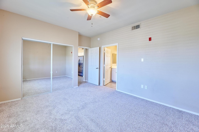 unfurnished bedroom with a closet, visible vents, light carpet, baseboards, and freestanding refrigerator