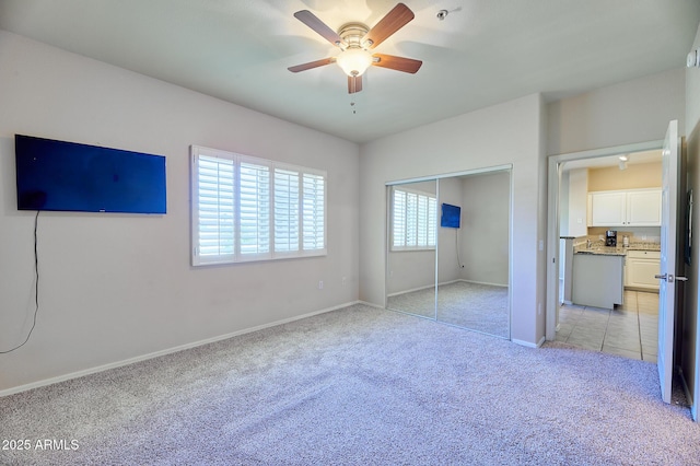 unfurnished bedroom featuring a closet, baseboards, a ceiling fan, and light carpet