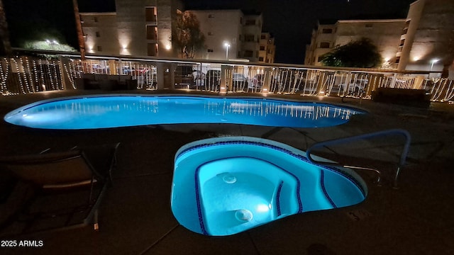 pool at twilight featuring a hot tub and a community pool