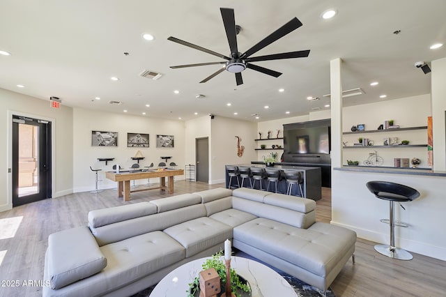 living room with baseboards, visible vents, ceiling fan, and light wood-type flooring