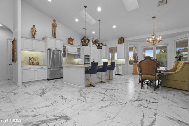 kitchen featuring a center island, tasteful backsplash, decorative light fixtures, white cabinetry, and stainless steel appliances