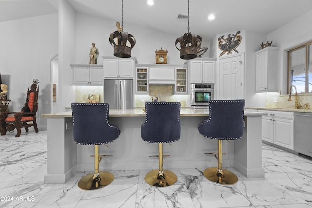 kitchen featuring lofted ceiling, white cabinets, a kitchen island, a kitchen bar, and stainless steel appliances