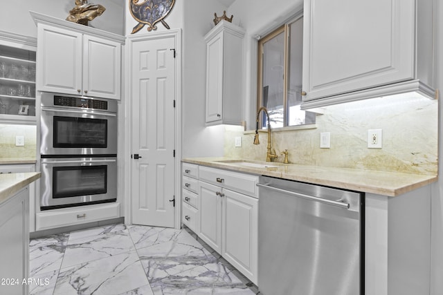 kitchen featuring white cabinets, sink, light stone countertops, appliances with stainless steel finishes, and tasteful backsplash