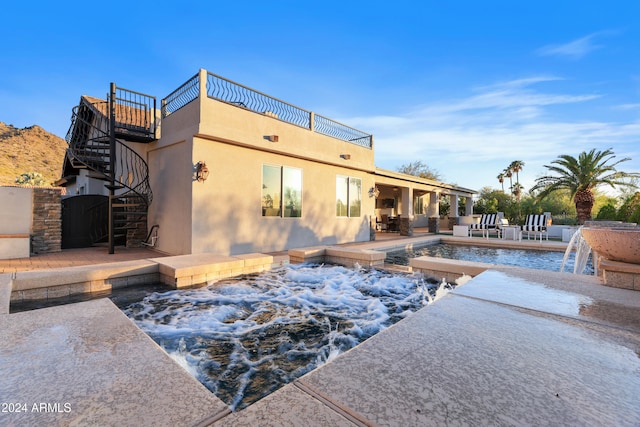 back of house with pool water feature, a balcony, a patio area, and a pool with hot tub