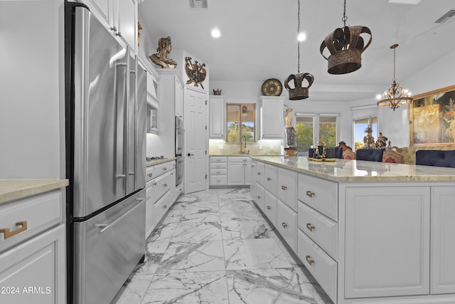 kitchen with high end refrigerator, light stone counters, white cabinets, a kitchen island, and hanging light fixtures