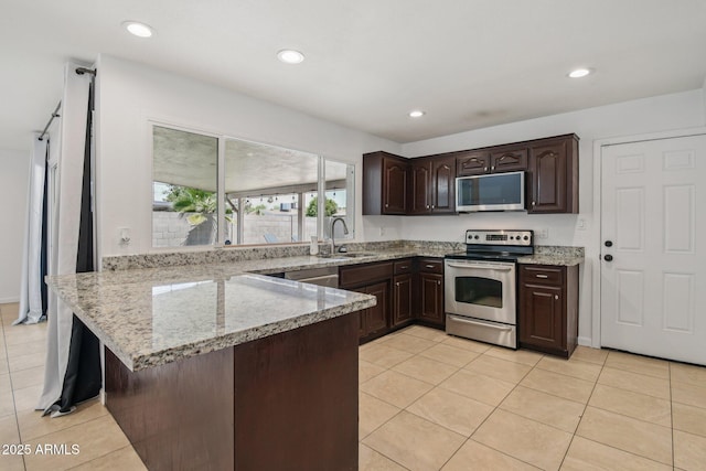2519 E Geneva Dr, Tempe, AZ 85282 - kitchen with stainless steel appliances, a peninsula, dark brown cabinetry, light tile patterned floors, and light stone counters