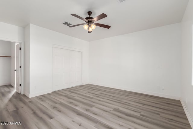 unfurnished bedroom with a closet, light hardwood / wood-style floors, and ceiling fan