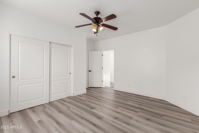 unfurnished bedroom with light hardwood / wood-style flooring, a closet, and ceiling fan