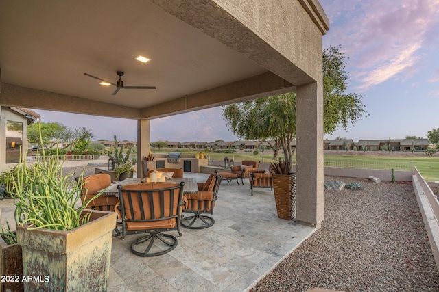 patio terrace at dusk featuring an outdoor living space and ceiling fan