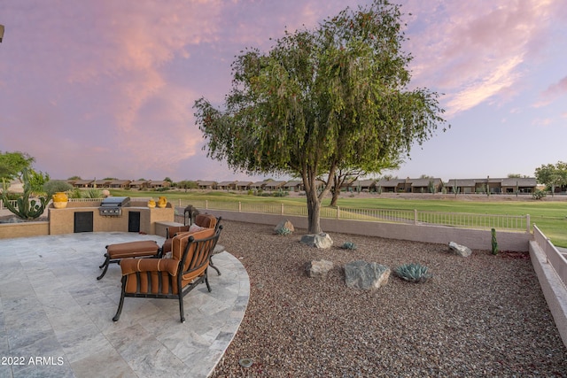 patio terrace at dusk featuring area for grilling