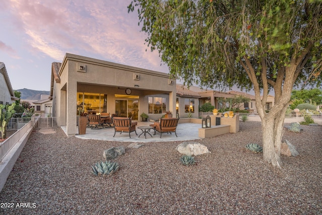 back house at dusk with a patio area and an outdoor living space with a fire pit