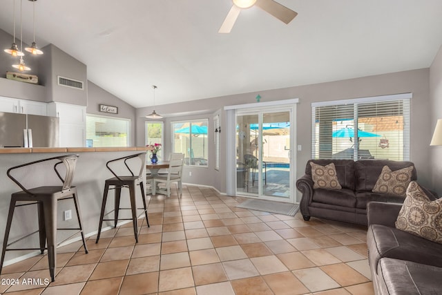 living room with ceiling fan, light tile patterned floors, and vaulted ceiling