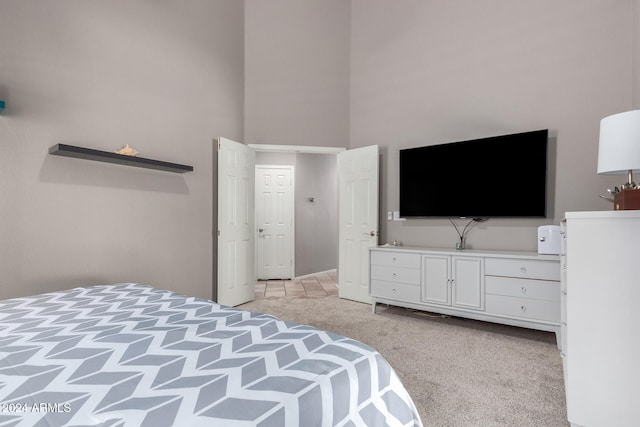 bedroom with light carpet and a towering ceiling