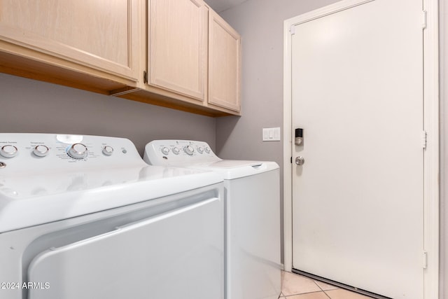 clothes washing area featuring washer and dryer, cabinets, and light tile patterned flooring