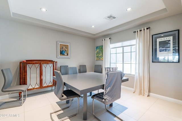 dining space featuring a raised ceiling and light tile patterned floors