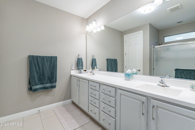 full bath featuring double vanity, a stall shower, visible vents, tile patterned flooring, and a sink