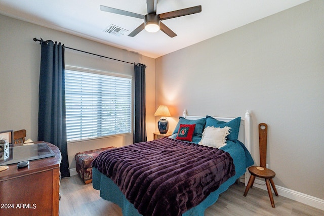 bedroom featuring light wood finished floors, a ceiling fan, visible vents, and baseboards