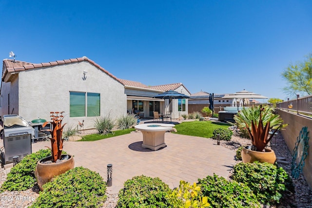 back of house with a tile roof, a patio area, a fenced backyard, and stucco siding